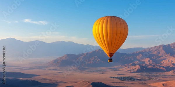 Fototapeta Soaring High: A vibrant hot air balloon drifts serenely over a vast desert landscape, set against a backdrop of majestic mountains and a clear sky.