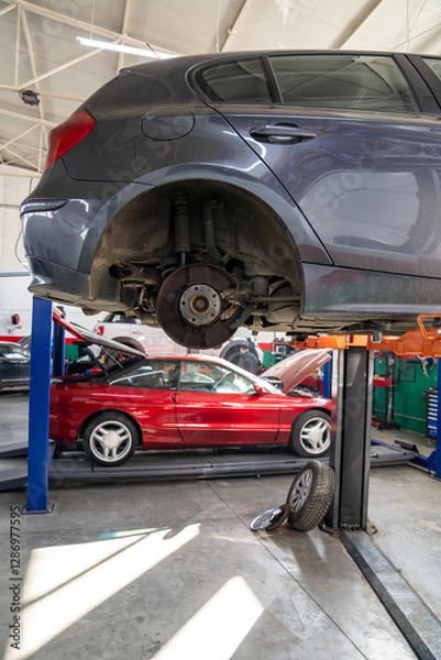 Fototapeta Car service workshop with cars on a column lifts