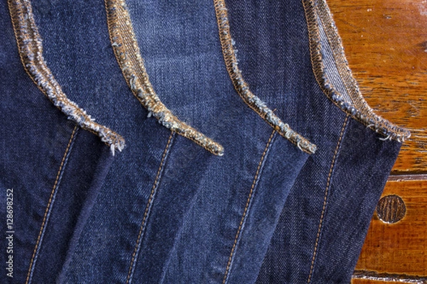 Obraz Jeans on a wooden background brown .Frayed Detail of nice