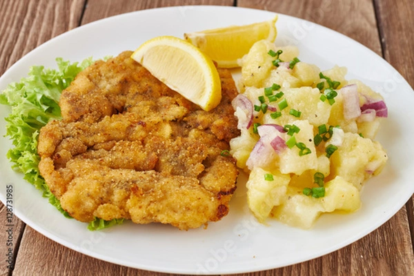 Fototapeta Weiner schnitzel with potato salad on a wooden background