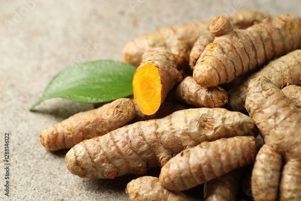 Fototapeta Pile of tumeric rhizomes with leaf on grey table, closeup
