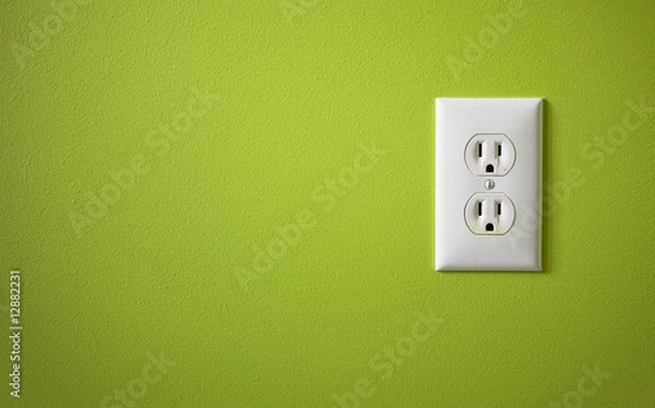 Obraz białe gniazdko elektryczne zamontowane na zielonej ścianie