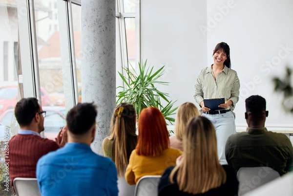 Fototapeta Woman Giving a Presentation to an Engaged Group in a Modern Setting