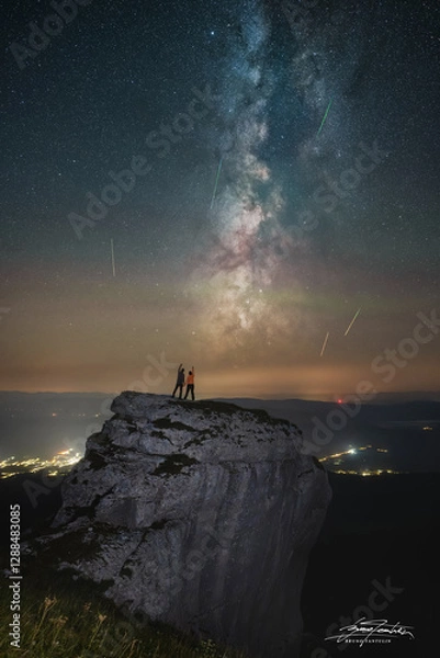 Fototapeta silhouette of a couple standing on a rock and watching perseid meteor shower
