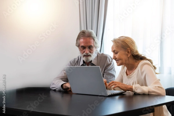 Obraz Happy Caucasian 70s mature couple using laptop at home. Old people using computer at home. Senior man and woman surfing the web on a wireless laptop connection. Modern retired lifestyle people.