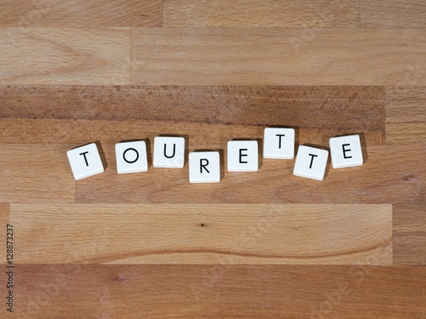 Fototapeta Tekst Tourette na powierzchni drewnianej. Zespół Tourette'a jest jednym z rodzajów zaburzeń tików. Tiki to mimowolne, powtarzające się ruchy i wokalizacje.