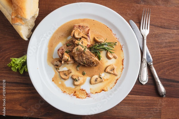 Obraz Concept: restaurant menus, healthy eating, homemade, gourmands, gluttony. White plate of pork medallions with mushroom sauce on weathered wooden table. Top-down view