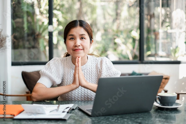 Fototapeta Young woman in a cozy cafe, working on a laptop, with a thoughtful expression. Natural light and greenery create a serene atmosphere.