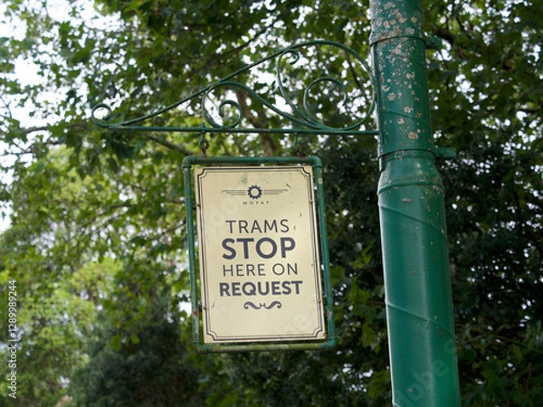 Fototapeta A sign says ' Trams Stop Here On Request' hanging from a post