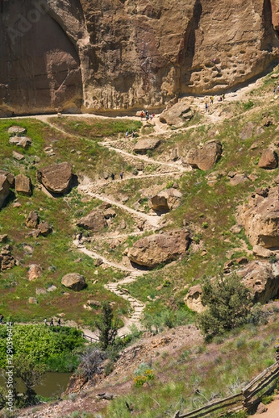 Fototapeta A winding path through rocky terrain leads hikers to breathtaking views, surrounded by unique rock formations and lush greenery under a bright sunny sky.