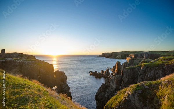 Fototapeta Dramatic sunrise on August morning.  Summer sun breaks  over the Atlantic ocean in Lancaster and Cable John Cove, Newfoundland, Canada.