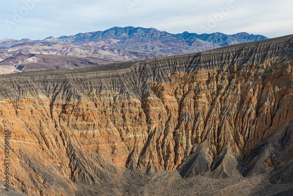 Fototapeta Striking stratified mountains display a mesmerizing array of colors, creating a stunning backdrop against a dramatic, cloudy sky, encapsulating the raw beauty of the Earth’s formations.