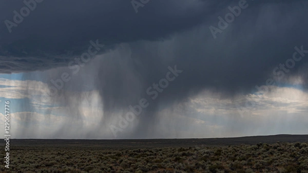 Fototapeta This dramatic image captures rain cascading down over an arid landscape, highlighting the contrast between dryness and moisture while emphasizing the beauty of nature's cycles.