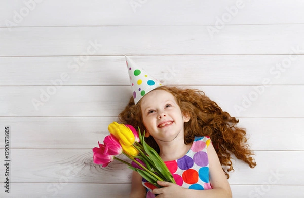 Obraz Happy girl smiling looking up, holding bouquet of tulips.