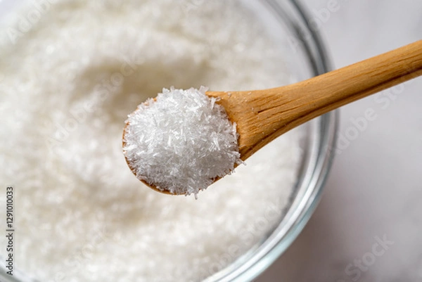 Obraz Wooden spoon full of monosodium glutamate over MSG white crystals in a glass bowl macro close-up. Concept of flavor enhancer food additive E621.