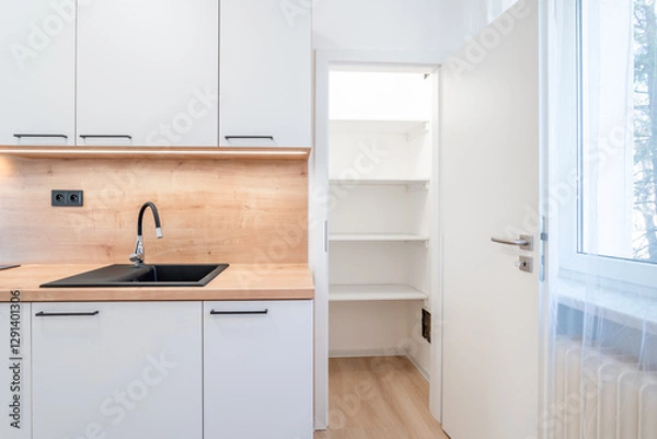 Fototapeta Modern white kitchen with open pantry door showing empty shelves and sink
