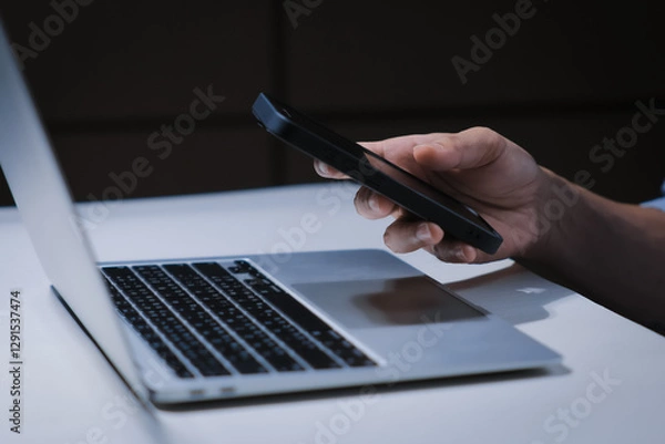 Fototapeta Cropped shot of young businessman hand typing on smartphone or laptop computer while working in office room.