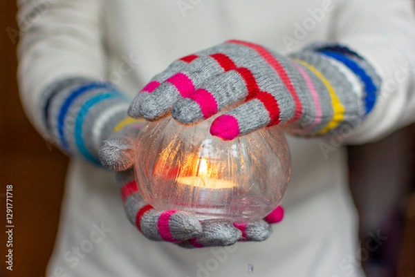 Fototapeta Gloved Hands Holding an Ice Lantern with candle in front of a window.
