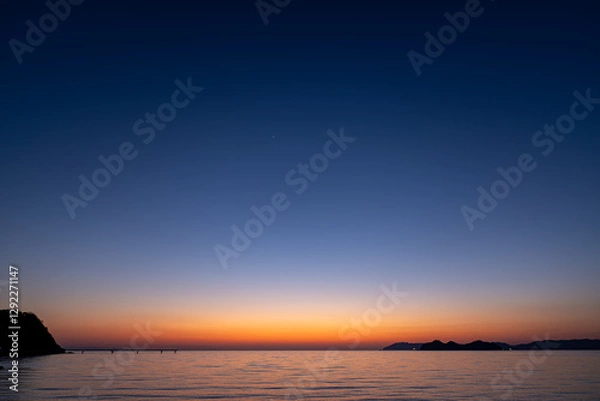Obraz 水平線に太陽が沈んだ後の穏やかな海岸