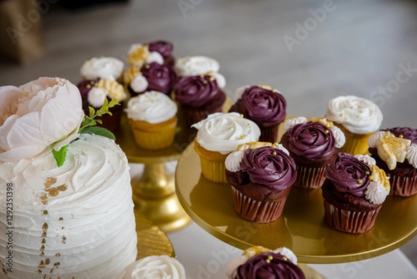 Fototapeta Elegant purple and white frosted cupcakes on gold display plates for wedding reception