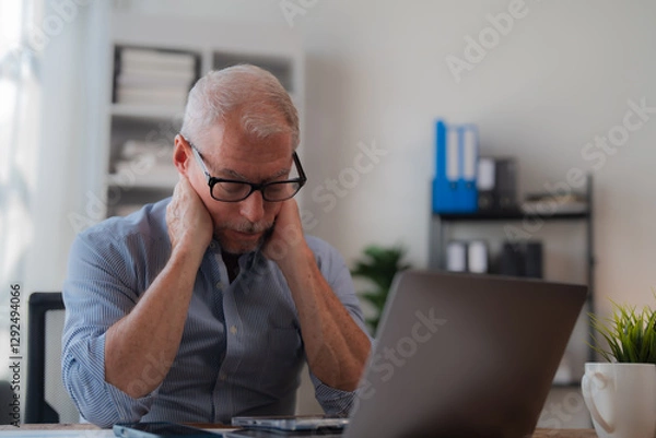 Fototapeta Tired businessman having neck pain while using laptop computer, senior office worker massaging his neck, feeling discomfort after long time working on computer, health problem concept