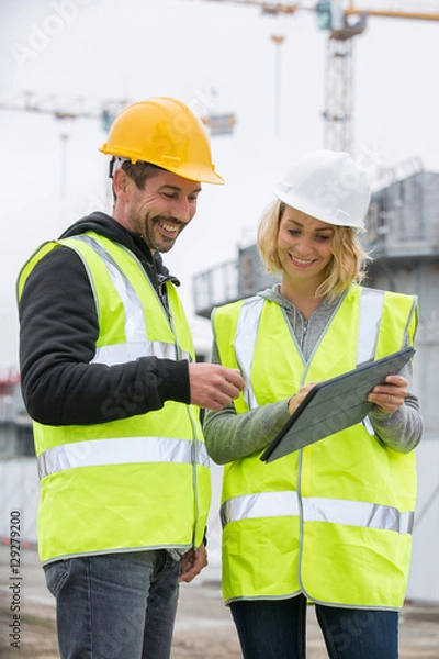 Obraz Woman in protective workwear and construction worker in construction site