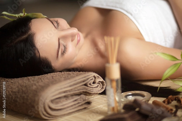 Fototapeta Top view of pretty woman laying in spa salon with closed eyes and relaxed