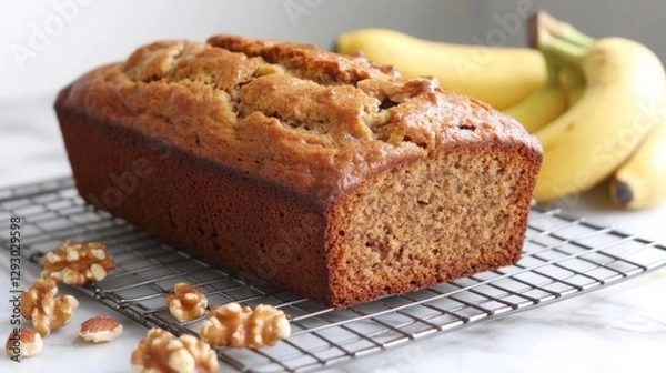 Fototapeta A loaf of banana bread cooling on a wire rack, surrounded by ripe bananas and a sprinkle of nuts, evoking a cozy baking atmosphere.