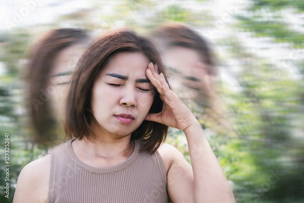 Obraz Asian woman suffering from anemia, experiencing syncope, dizziness, and vertigo while walking outdoor due to reduced oxygen levels