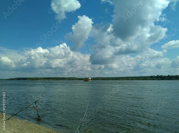 Fototapeta Summer evening landscape with beautiful clouds over the river, the edge of the shore with 2 fishing rods
