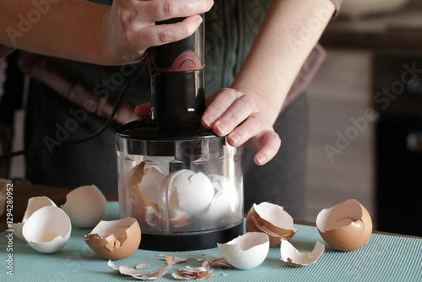 Fototapeta Preparing Eggshell Powder. Woman grinds eggshells with blender. Calcium supplement, cracked eggshell, natural compost ingredient, broken eggshell