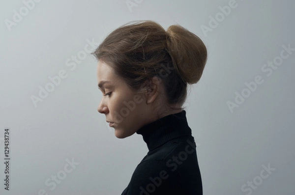 Fototapeta Dramatic portrait of a young beautiful girl with freckles in a black turtleneck on white background in studio