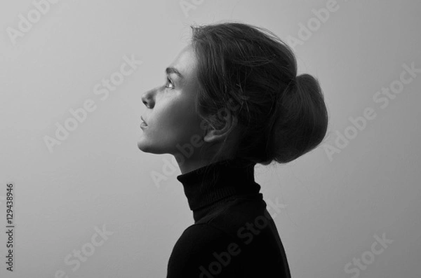 Fototapeta Dramatic black and white portrait of young beautiful girl with freckles in a black turtleneck on white background in studio