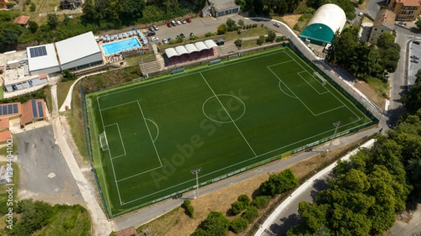 Fototapeta Aerial view of a soccer field with synthetic grass in a sports center with a swimming pool.