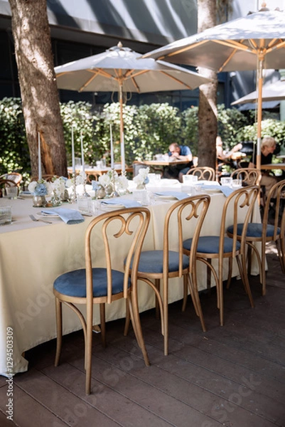 Fototapeta Seating for guests at a table in a restaurant on a terrace in summer. Sunlight and dishes on the table luxury decor