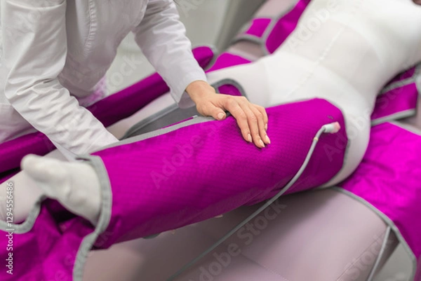 Fototapeta A therapist fastening a pressotherapy leg sleeve on a patient, preparing for a professional lymphatic drainage session.
