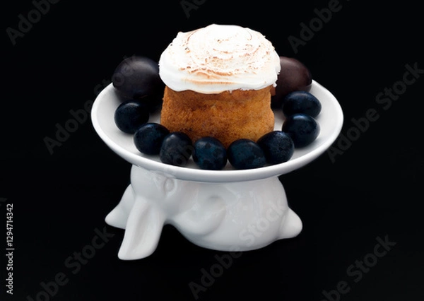 Fototapeta Easter cake on a white plate in the shape of an Easter bunny with Easter eggs on a black background