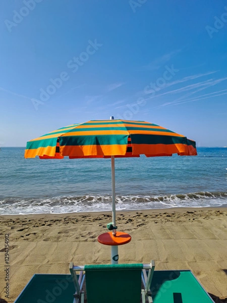Fototapeta Orange and green beach umbrellas. Blue sky. Relaxing context. Summer holidays at the sea. General contest and location