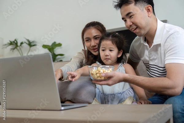 Fototapeta Family sharing popcorn and enjoying a movie together on a laptop.