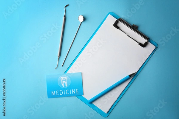 Obraz Business card, clipboard and dental tools on blue background. Medical service concept