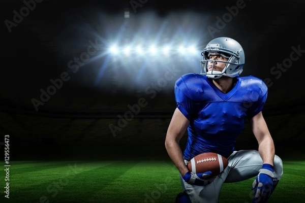 Fototapeta Composite image of american football player with ball kneeling