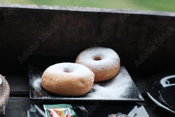 Obraz Fresh donuts sprinkled with powdered sugar, perfect for breakfast or a sweet snack.