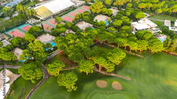 Fototapeta Aerial view of a luxury resort with golf course, tennis courts, and private villas among lush greenery