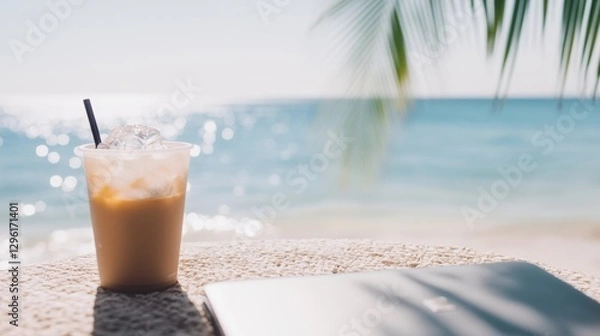 Obraz Beachside workspace setup featuring a laptop, iced coffee, and notebook with palm trees and turquoise waters in the background