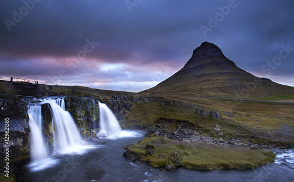 Fototapeta cloudy sunset the top of Kirkjufellsfoss waterfall with Kirkjufell mountain in the background on the north coast of Iceland's Snaefellsnes peninsula taken white a long shutter speed.