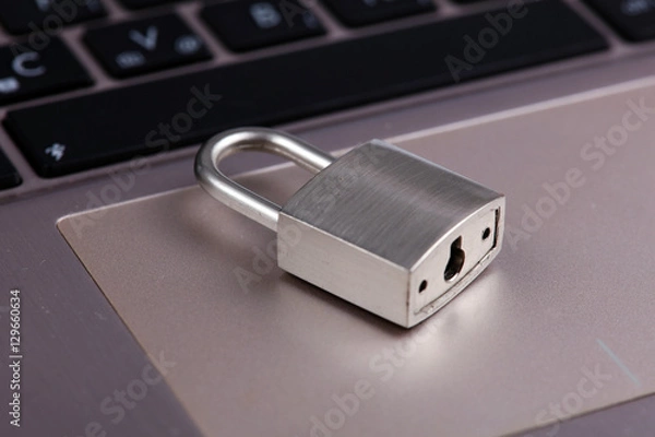 Fototapeta Padlock on silver aluminium notebook, laptop. Internet, web safety, privacy and security concept.