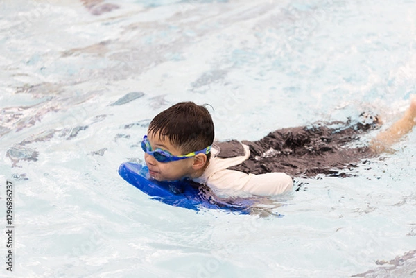 Obraz Boy is swimming in a pool with a blue float
