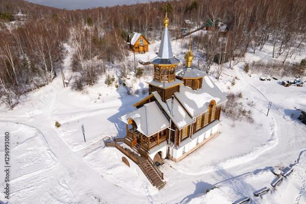 Fototapeta Aerial top view to wooden church of Transfiguration covered snow of the Lord on mountain near village Port Baikal. Frozen ice Lake and river Angara on backgroud. Winter landscape Siberia, Russia.