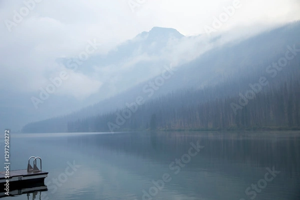 Fototapeta Fog hanging over mountain lake and forest with dock
