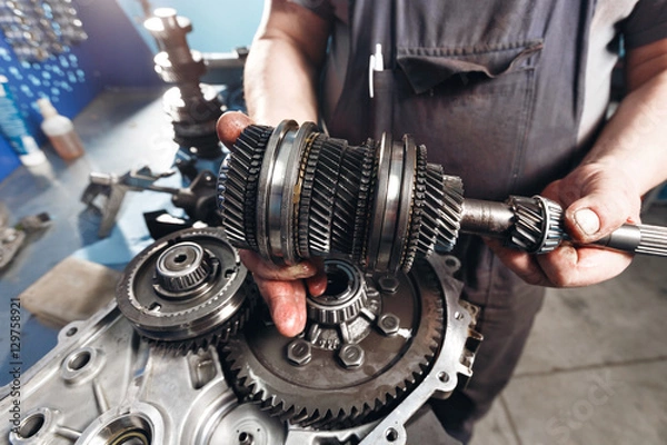 Fototapeta Przekrój skrzyni biegów samochodowych. Mechanicy pracują w garażu. Mechanik ręczny w ubraniach roboczych